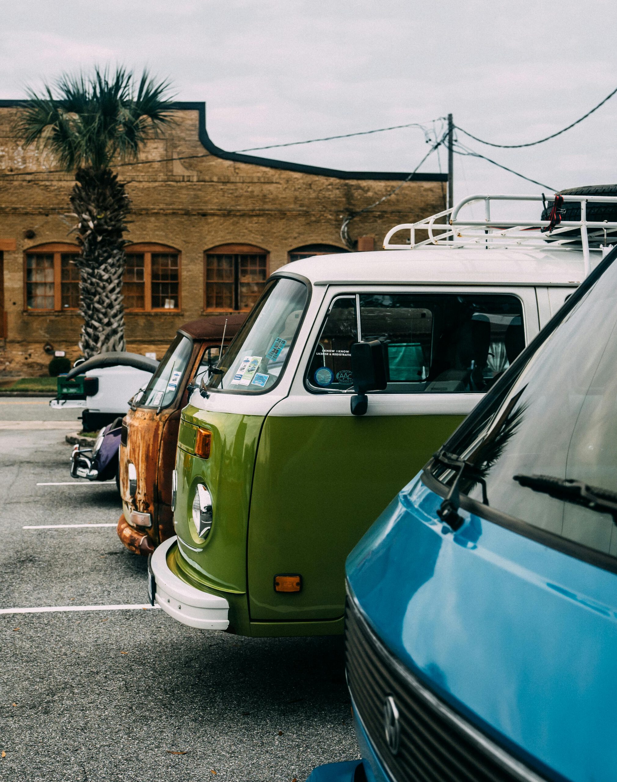 A lineup of vintage Volkswagen vans parked in a city parking lot, showcasing retro automotive style.