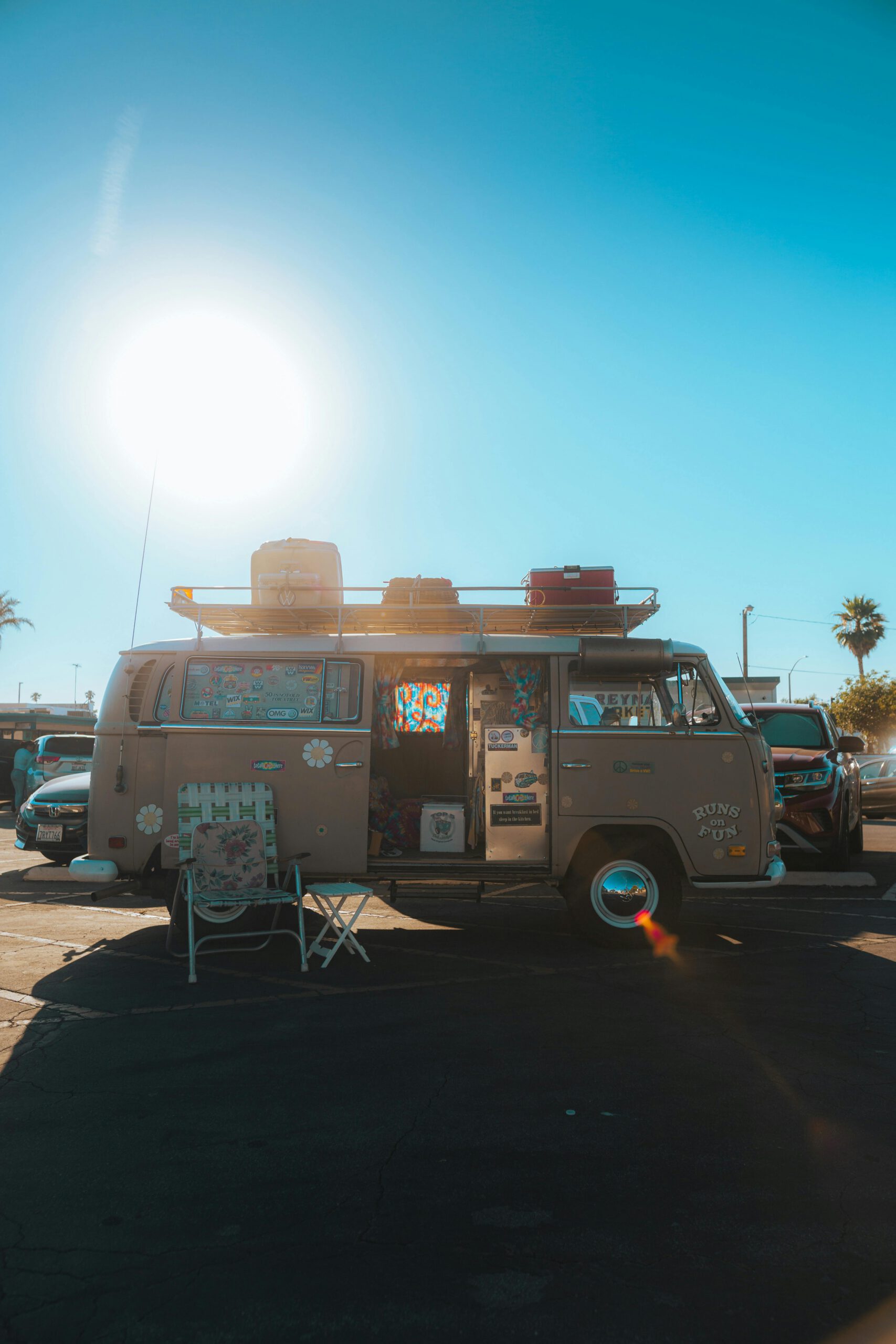 Vintage camper van in a sunny parking lot with travel gear aboard.