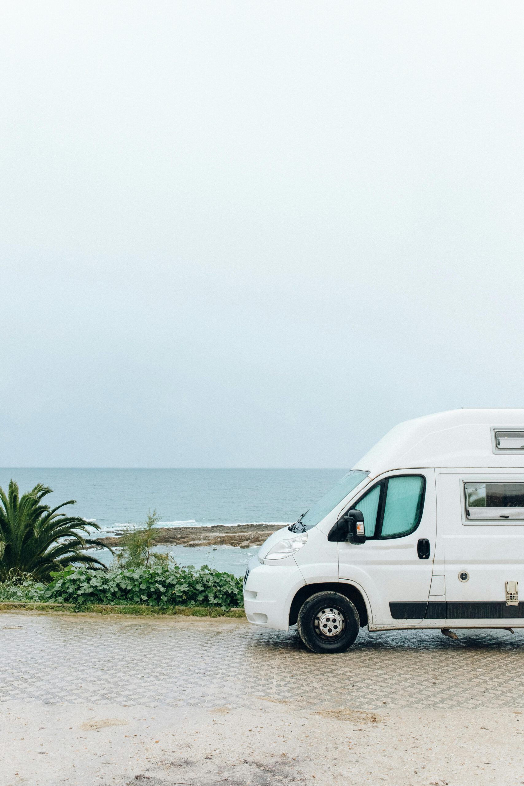 White van parked by the sea with a scenic view, perfect for travel and adventure enthusiasts.